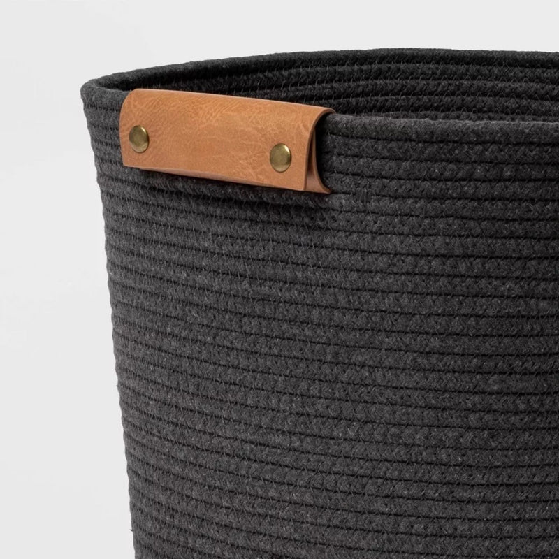 Load image into Gallery viewer, Close-up of the Brightroom™ gray rope basket&#39;s side, showing the intricate coiled design and one leather handle with brass fixtures.
