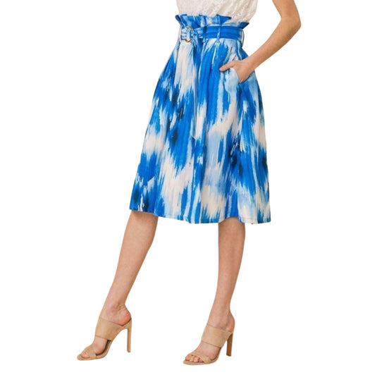 Detail-oriented view of a tie-dye blue and white midi skirt with pleats and a cinched paper bag waist, highlighting the stylish belt and texture of the fabric.