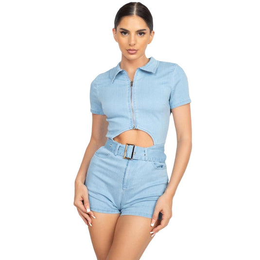 Model posing in a light blue belted zip-up denim romper with front zipper and cutout detail.