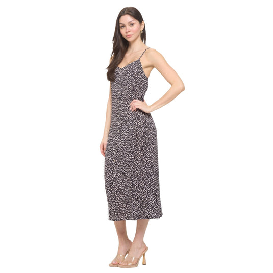 Side view of a woman modeling a black floral spaghetti strap maxi dress, featuring a mid-length cut and flowy silhouette.