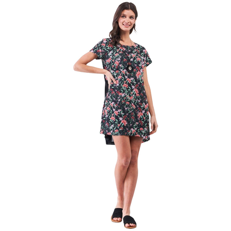 Load image into Gallery viewer, A full-body view of a woman showcasing a black floral-print mini dress with a pleated back detail, paired with black sandals for a relaxed yet stylish look.
