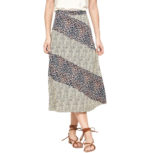Colorblock floral midi skirt with a mix of beige and dark print patches, matched with a simple white tee and brown strappy sandals for a casual look.