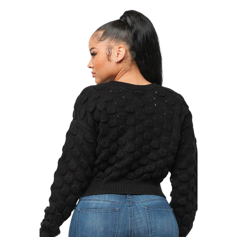 Load image into Gallery viewer, Back view of a woman looking over her shoulder, wearing a black sweater with a raised checker pattern.
