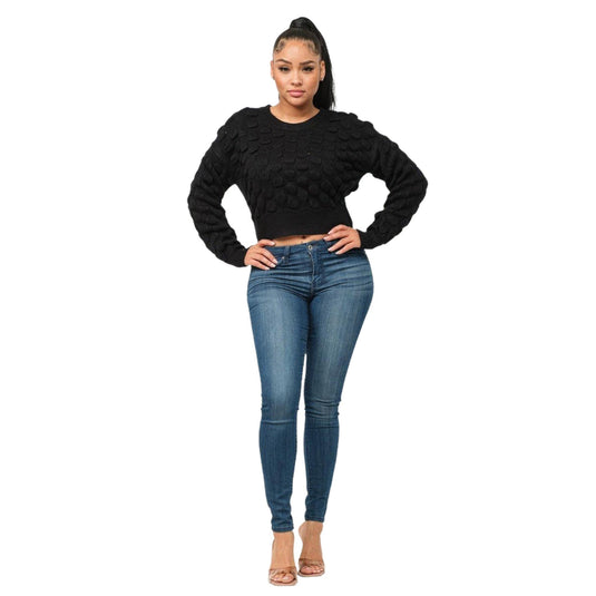 Front view of a woman wearing a black textured sweater and denim jeans, exuding casual elegance.