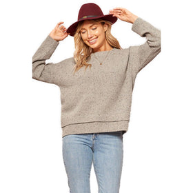 Woman smiling wearing a casual oatmeal flecked crewneck sweater and maroon hat, exuding a relaxed style.
