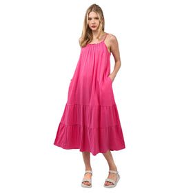 Model wearing a pink cotton gauze A-line midi dress with adjustable straps and side pockets, standing in a front view.