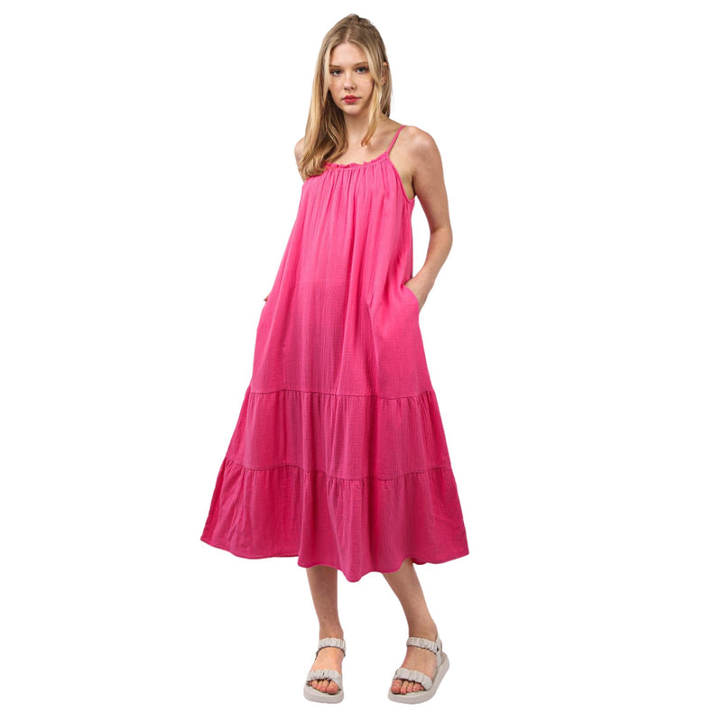 Load image into Gallery viewer, Model wearing a pink cotton gauze A-line midi dress with adjustable straps and side pockets, standing in a front view.
