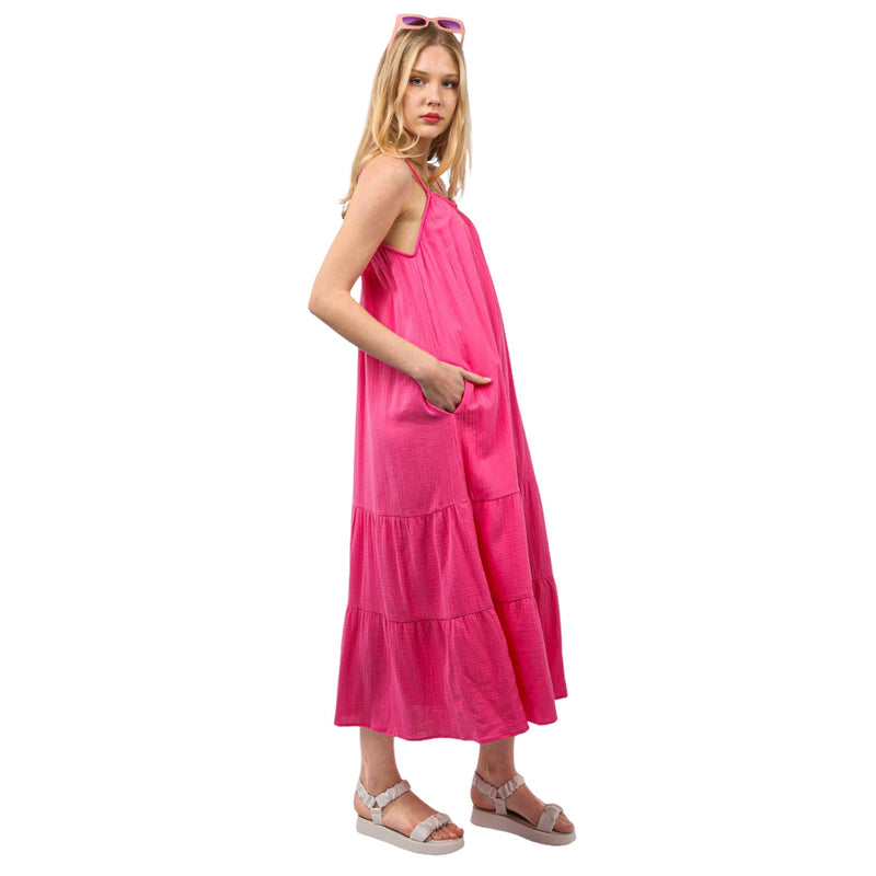 Load image into Gallery viewer, Model posing in a side view of a pink cotton gauze A-line midi dress, highlighting the side pockets and relaxed fit
