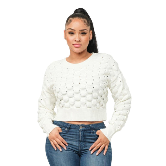 Confident woman posing in a cream puffy checker sweater top with a cropped fit, paired with blue denim jeans.