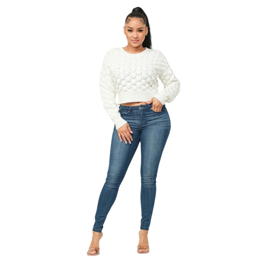 Full-length view of a model showcasing a cream textured sweater with a unique puffy checker pattern and slim-fit jeans.