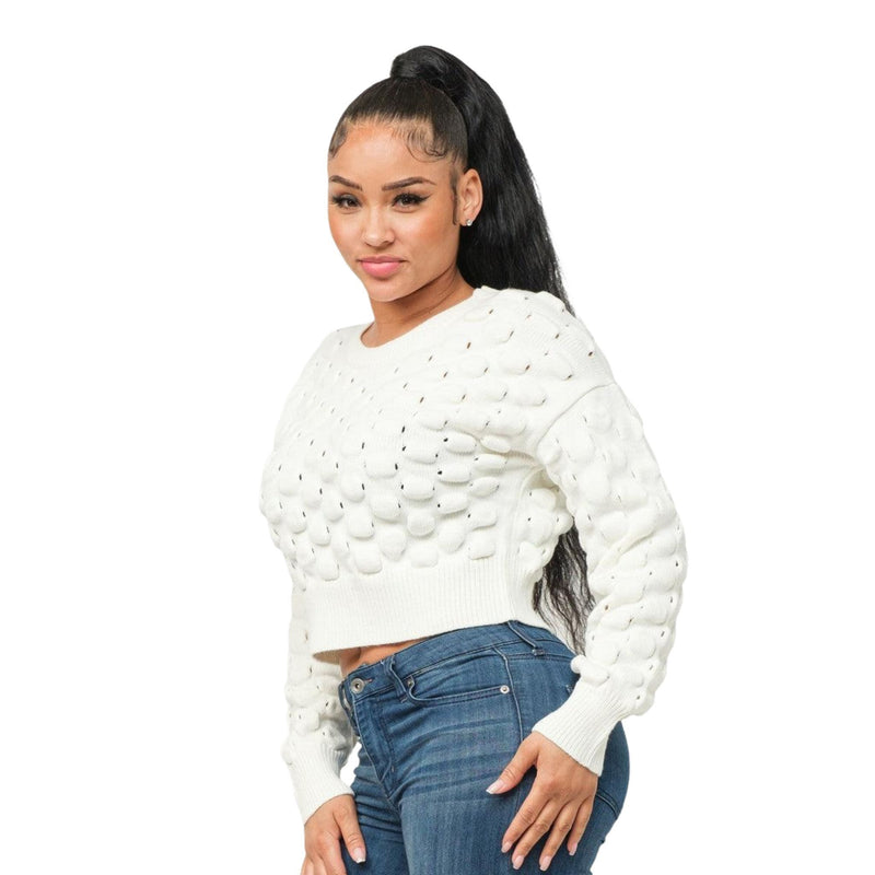 Load image into Gallery viewer, Side view of a woman modeling a cream-colored, puffy checker-textured sweater, paired with form-fitting blue jeans, showcasing the sweater&#39;s unique design and cozy fit.
