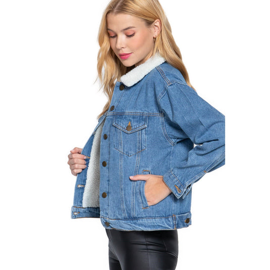 Side view of a woman sporting an oversized dark blue denim jacket with a cozy white fur lining, open to reveal the outfit underneath.