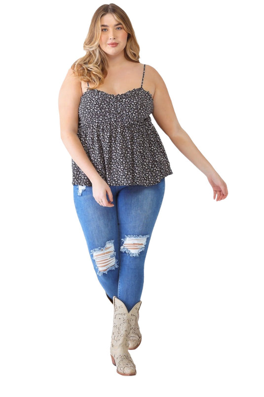 Plus-size model in a black floral smocked sweetheart neck cami, paired with distressed jeans and cowboy boots, showcasing a trendy casual outfit.