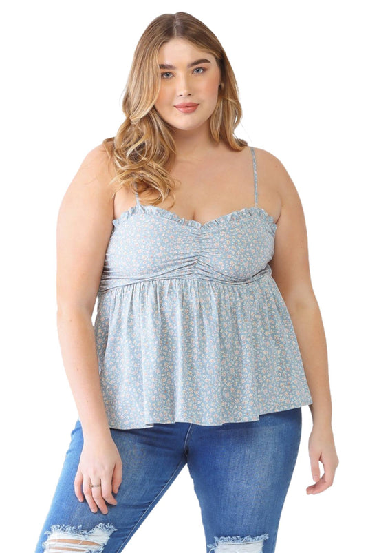 Plus-size model in a blue floral smocked sweetheart neck cami and distressed jeans, paired with cowboy boots, showcasing a casual, stylish look.