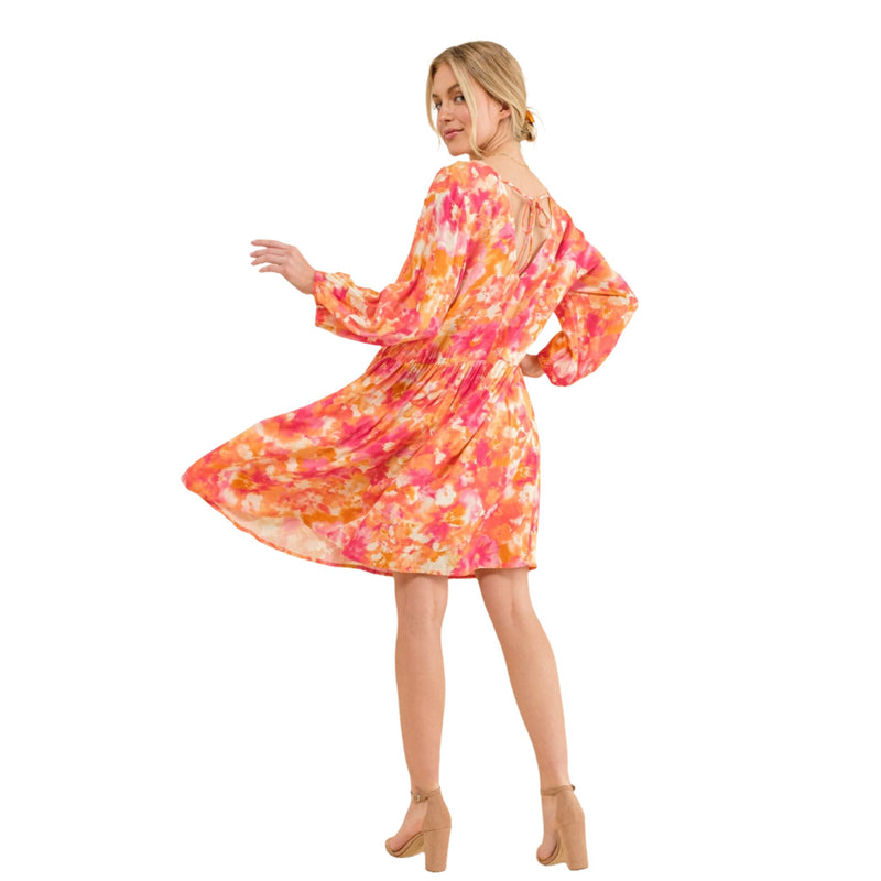 Load image into Gallery viewer, Back view of a woman twirling in a floral V-neck dress with puff sleeves, showcasing the dress&#39;s loose and comfortable fit.
