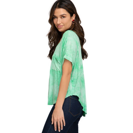 Three-quarter rear view of a woman in a light green tie-dye top with a V-neck and drop shoulders, highlighting the airy and loose fit.