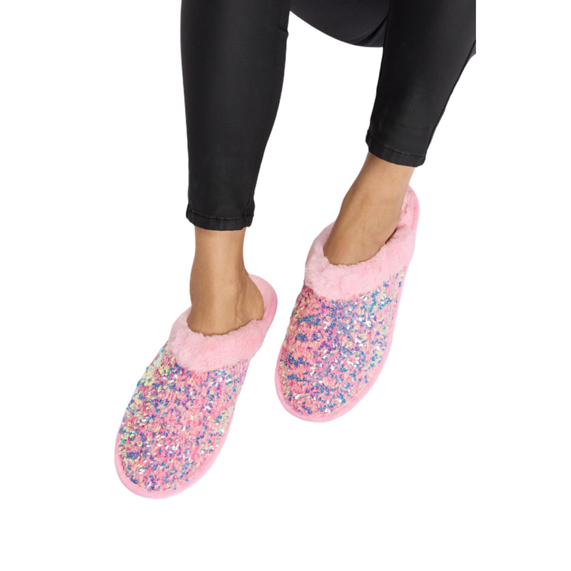 Load image into Gallery viewer, Front view of pink sequin plush slippers with fuzzy lining, being worn while seated. The slippers have a cozy, warm look and feature a round toe design.
