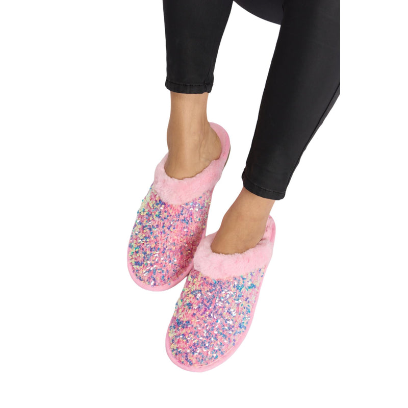 Load image into Gallery viewer, Overhead view of pink sequin plush slippers with shimmering sequins, being worn by someone sitting cross-legged. The fluffy pink lining is visible, adding to the cozy appearance.
