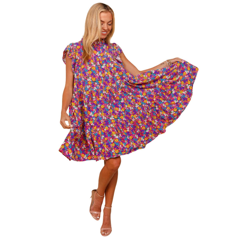 Load image into Gallery viewer, Woman wearing a frilled mock neck ditsy floral dress in vibrant colors, twirling to show off the flowy skirt.
