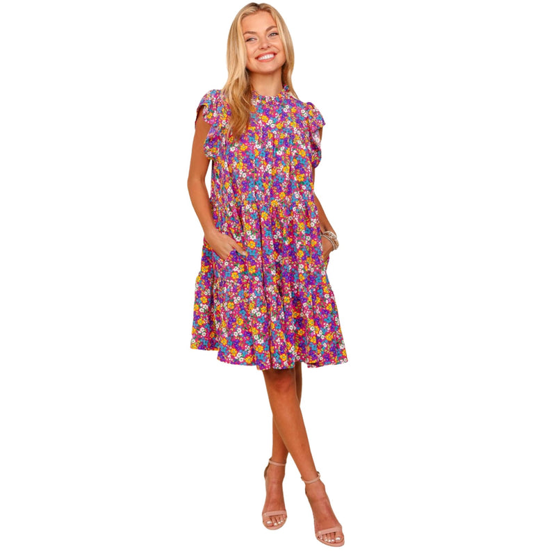 Load image into Gallery viewer, Front view of a woman in a frilled mock neck ditsy floral dress, showcasing the detailed floral design.
