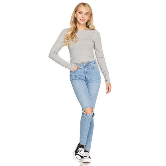 Casual-chic style with a woman in a grey ribbed crop top and distressed blue jeans, complete with black and white sneakers.