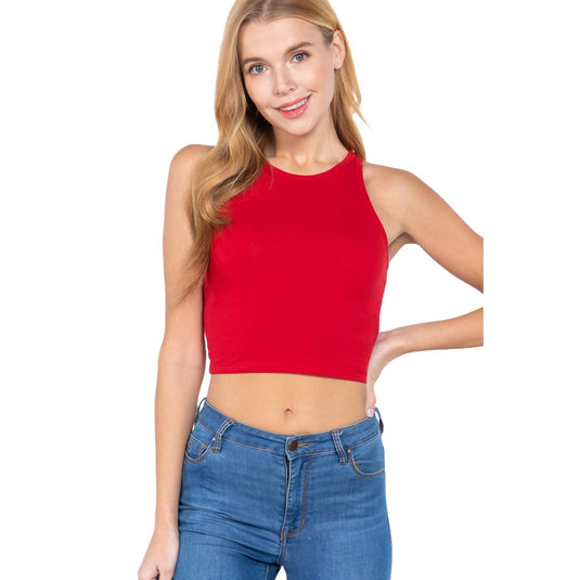 The image features a woman posing in a sleeveless red crop top with blue jeans against a plain background. The crop top has a high neckline and provides a bold pop of color that stands out.