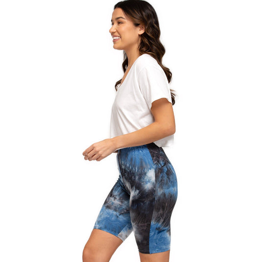 Side profile of a woman walking and wearing blue and grey tie-dye high-rise biker shorts with a comfortable white tee.