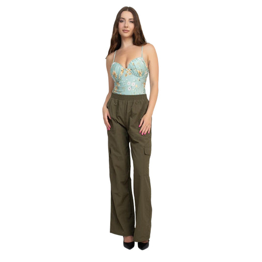 Full-body view of a woman wearing olive green high-rise cargo parachute pants paired with a floral print bustier top. The pants have an elastic waistband and multiple pockets, creating a trendy and comfortable outfit.