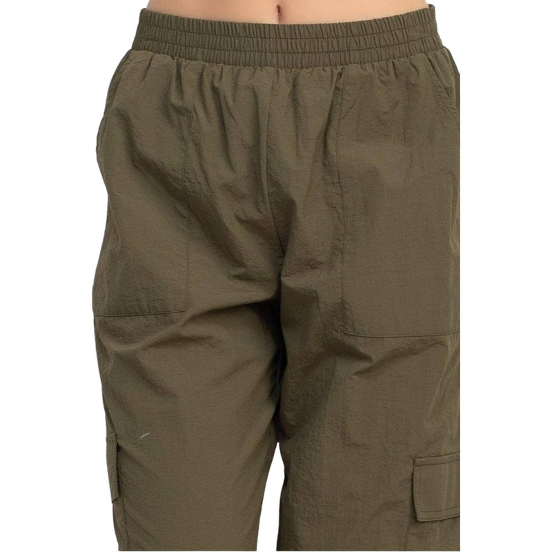 Load image into Gallery viewer, Close-up view of the waistband and upper part of olive green high-rise cargo parachute pants. The pants have an elastic waistband and a relaxed fit, emphasizing comfort and practicality.
