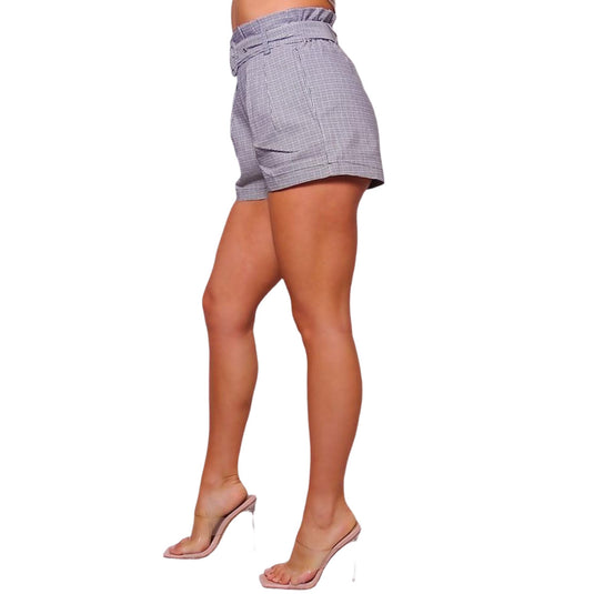 Side view of a stylish ensemble showcasing high-waisted plaid shorts with a matching belt, accentuating the waistline, complemented by a sleeveless top and transparent high heels.