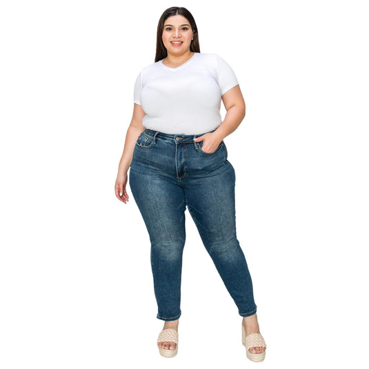 Plus-size woman smiling, dressed in a white short-sleeve shirt tucked into high-waisted dark wash jeans, posing with one hand in her pocket.