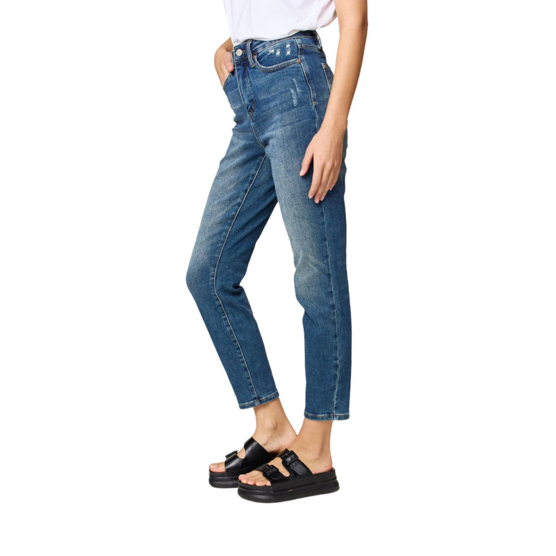 Load image into Gallery viewer, A profile shot of the model showing the side fit of the blue high-waisted jeans, with slight fading along the thighs and distressing near the front pocket.
