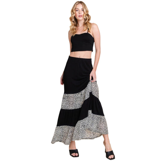 Fashionable black tiered maxi skirt with contrasting animal print, shown on a model in a dynamic walking pose, highlighting the skirt's flow.