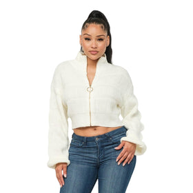 Elegant woman in a cropped white knitted sweater with a front zipper and long lantern sleeves, paired with blue jeans.