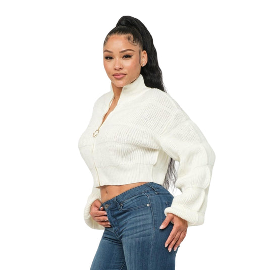 Side pose of a woman showcasing a white sweater with unique sleeve detailing and a circular zipper pull.