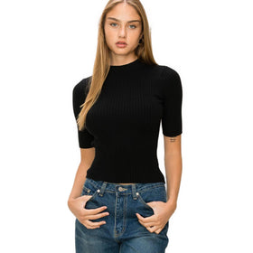 A model confidently wears a black mock neck ribbed sweater with elbow-length sleeves, paired with classic blue jeans.