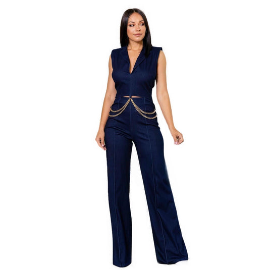 Front view of a woman modeling a navy denim stretch jumpsuit with a sophisticated chain waist detail.