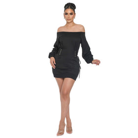 Full body view of a woman wearing an off-shoulder black mini dress with puff sleeves and side lace-ups. The dress combines a trendy off-shoulder neckline with fashionable lace-up details on the sides, ideal for a contemporary and stylish look.