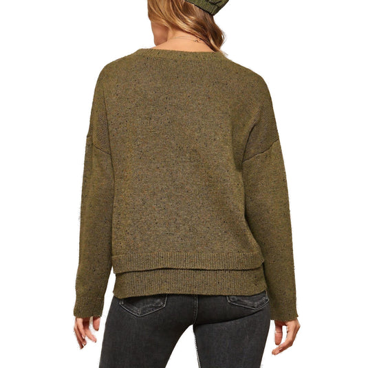Rear view of a woman wearing an olive green knit sweater that features a relaxed fit, teamed with dark gray skinny jeans.