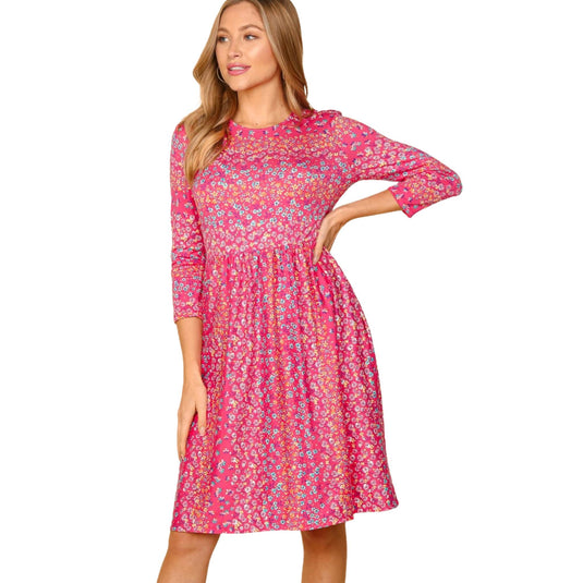 Woman wearing a pink floral dress with three-quarter sleeves, showing a close-up view of the dress's pattern and fit.