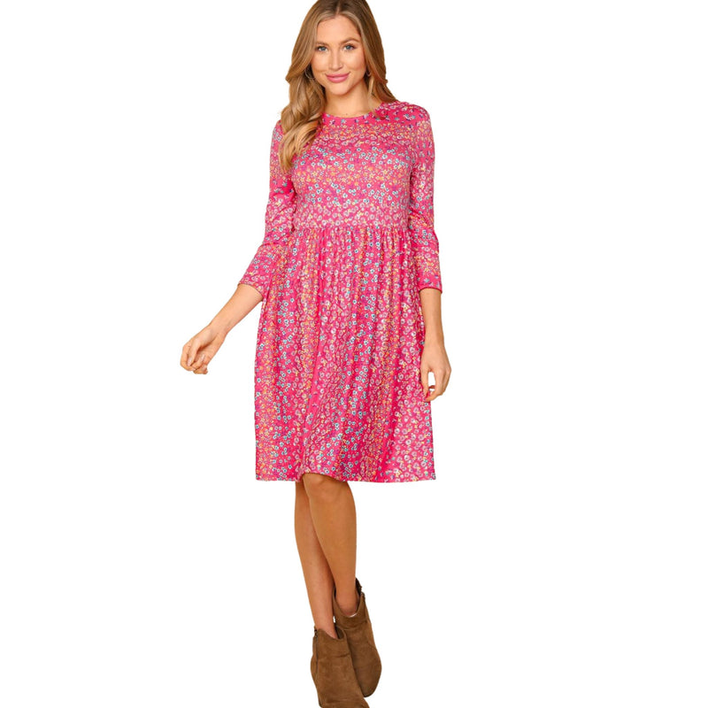 Load image into Gallery viewer, Woman in a pink floral dress with three-quarter sleeves, standing with one hand on her hip, highlighting the dress&#39;s length and style.
