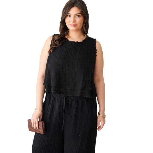 Confident plus-size model in a sleeveless black top with frayed neckline detail, creating a chic bohemian look.