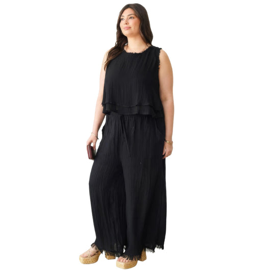 Full-length view of a fashionable outfit featuring a black bohemian frayed hem top paired with wide-leg jeans and wedge sandals.