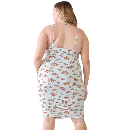 Back view of a plus-size model in a light floral ruched cami dress, highlighting adjustable straps and ruched detailing, paired with beige cowboy boots.