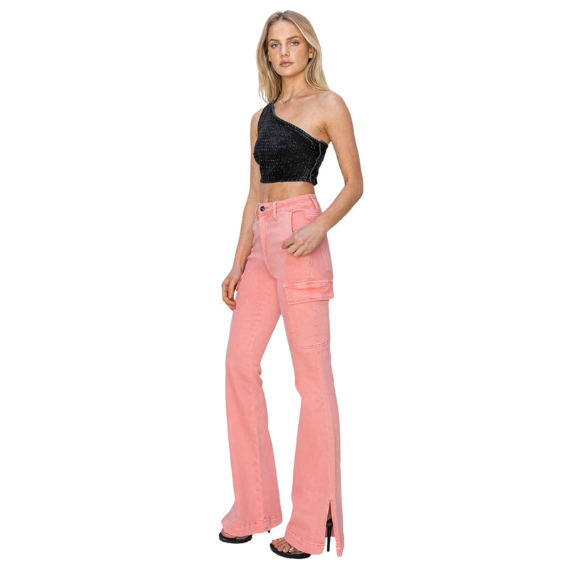 Load image into Gallery viewer, Woman wearing pink high-rise bootcut cargo jeans with side slits, paired with a black one-shoulder crop top, standing in a side profile.
