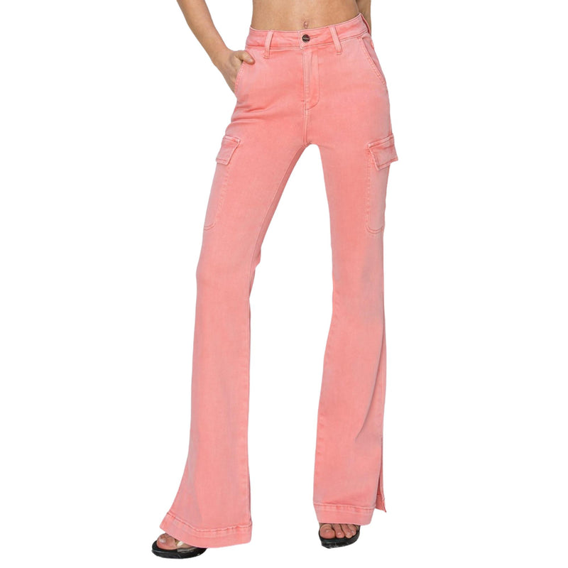 Load image into Gallery viewer, Front view close-up of pink high-rise bootcut cargo jeans, highlighting the cargo pockets and side slit, with the woman’s hand in her pocket.
