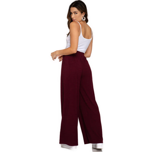 Rear view of Wine-Colored Rib Knit Wide Leg Long Pants on a woman, highlighting the relaxed fit and the elegant drape of the fabric. The drawstring and elastic waistband provide a snug, adjustable fit.