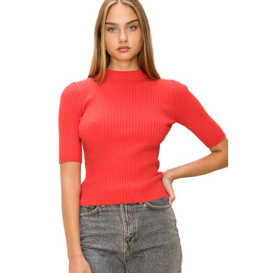 Striking red ribbed mock neck sweater showcased on a model, paired with casual grey jeans for a pop of color.