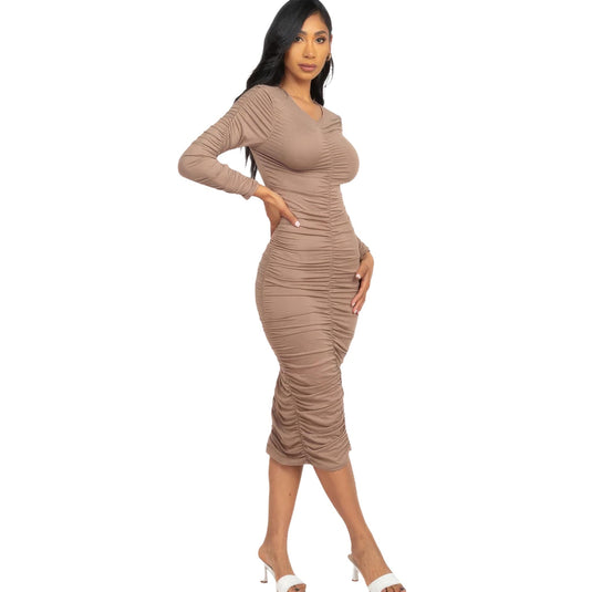 Elegant lady in a taupe grey ruched long sleeve midi dress, striking a poised stance with white heels, perfect for any sophisticated setting.