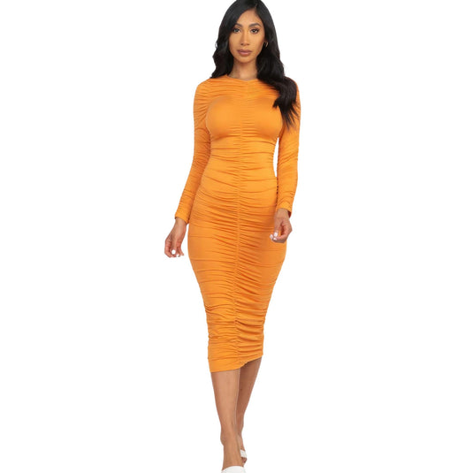 Elegant woman in a ruched long sleeve midi dress in vivid mango, paired with white heels for a chic look.